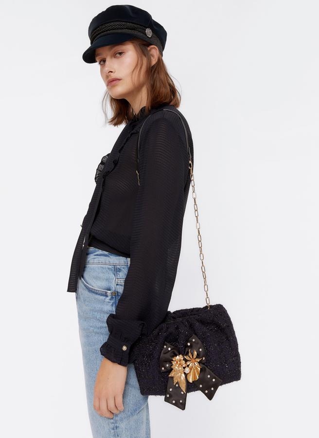 Las amantes del barroco también tienen su modelo con cadena. La lleva en el asa, pero pasa a un segundo plano con esa maravilla de lazo y detalles dorados. Es un bolso de Uterqüe (69 euros).