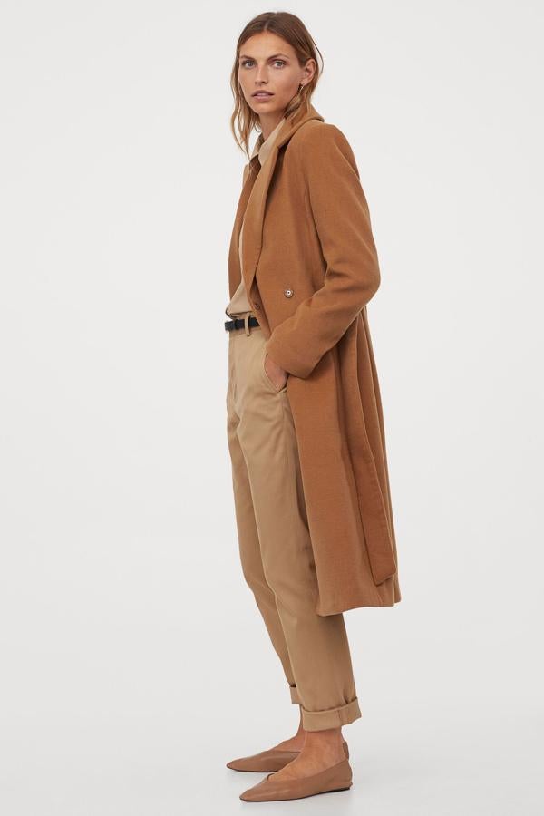 Este modelo de abrigo camel de H&M también tiene cinturón, pero se diferencia de los demás en que también se cierra con botones automáticos. Está disponible en más colores y su precio es imbatible (49,99 euros).