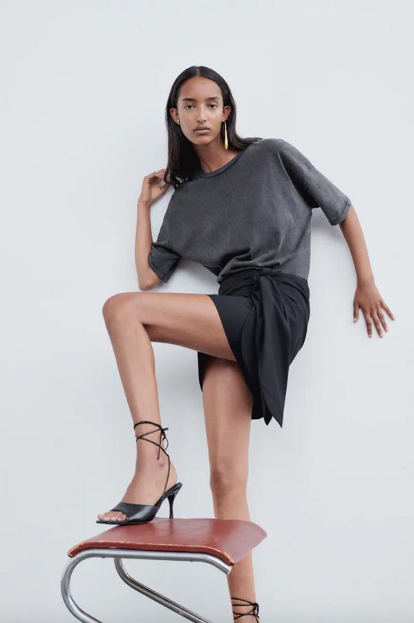 De tiro alto en color negro, esta falda mini de Zara viene con detalle de nudo en el lateral y tiene un precio de 29,95 euros. Podemos encontrarla entre las tallas XS y XXL.