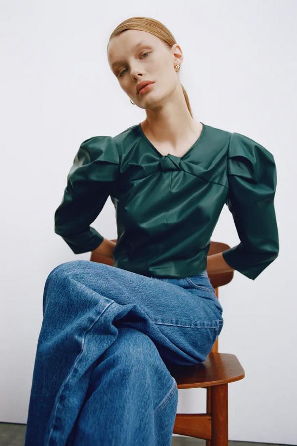 Este top cropped en verde oscuro es de Zara y viene con cuello redondo, manga por debajo del codo abullonada en el hombro y detalle de nudo en la zona del escote. Con un precio de 25,95 euros, está disponible entre las tallas XS y XL.