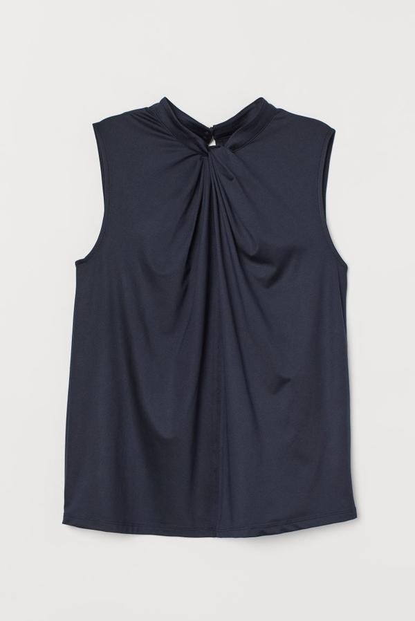 Este top en azul oscuro de H&M sin mangas está confeccionado en punto ligero con brillo. Con cuello elevado corto con detalle de nudo en el frontal, cuesta 14,99 euros y está disponible entre las tallas XS y L.