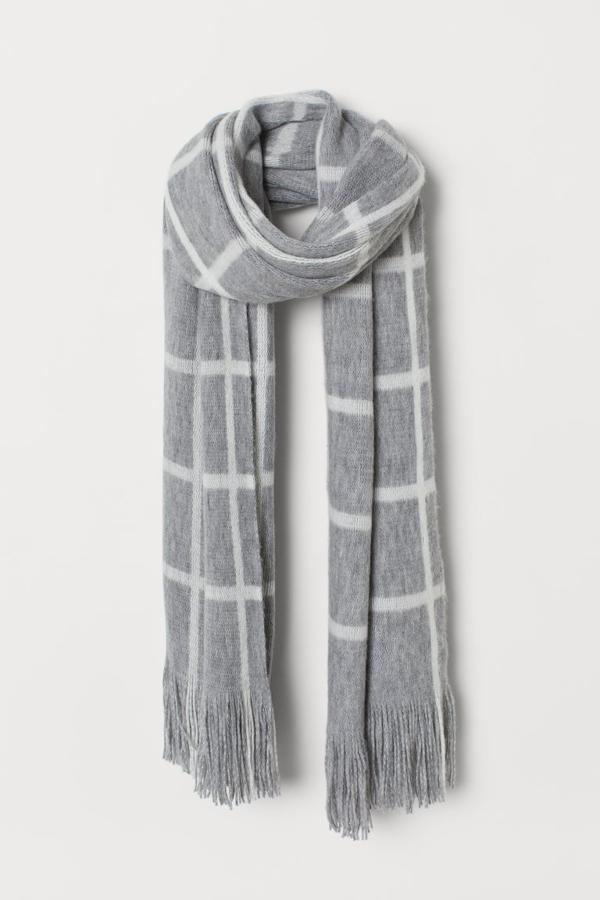 En punto fino suave, con flecos en los extremos, esta bufanda en gris claro con cuadros blancos es de H&M y cuesta 9,99 euros.