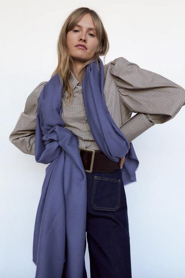 Disponible en cinco tonos diferentes, entre ellos el negro, el gris o el índigo, esta bufanda de tacto suave con acabado desflecado de Zara tiene un precio de 19,95 euros.