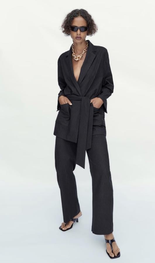 Americana fluida sin botones que se abrocha con cinturón, en un tono gris oscuro, de Zara (49,95 euros). Tiene el pantalón a juego.