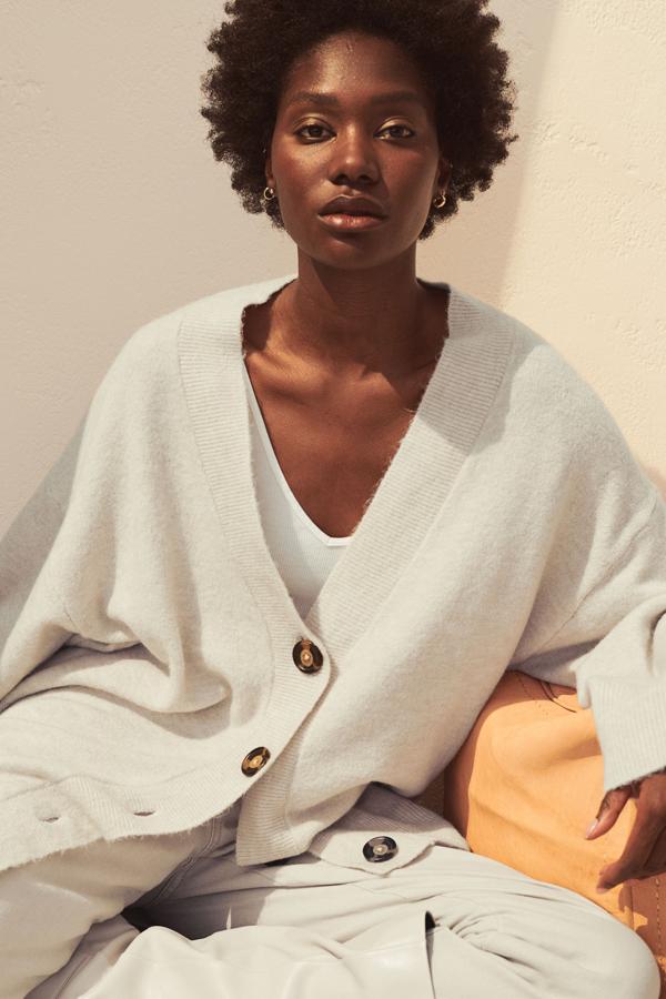 Disponible en beige claro, negro y gris, este cárdigan de H&M en diseño oversize está confeccionado con poliéster reciclado en punto suave con lana en la trama. Tiene el escote de pico, hombros caídos y ribete de canalé en tapeta, puños y bajo. Con cierre frontal de botones en carey, podemos encontrarlo entre las tallas XS y XL por 24,99 euros.