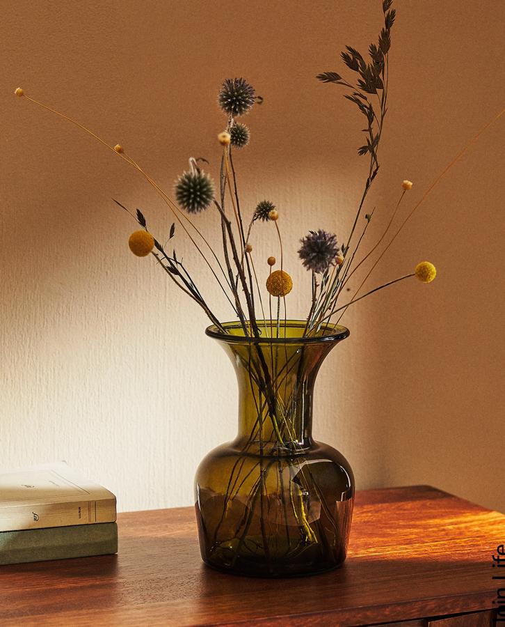 Disponible en verde, ocre o marrón, este jarrón de vidrio reciclado tiene unas medidas de 14x20x14 centímetros y un precio de 15,99 euros.