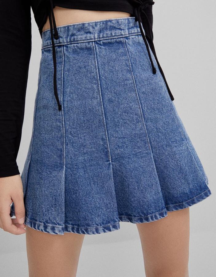 De tiro alto, en tejido denim, con tablas en el bajo, esta falda mini de Bershka está disponible entre las tallas 32 y 38 por 25,99 euros.