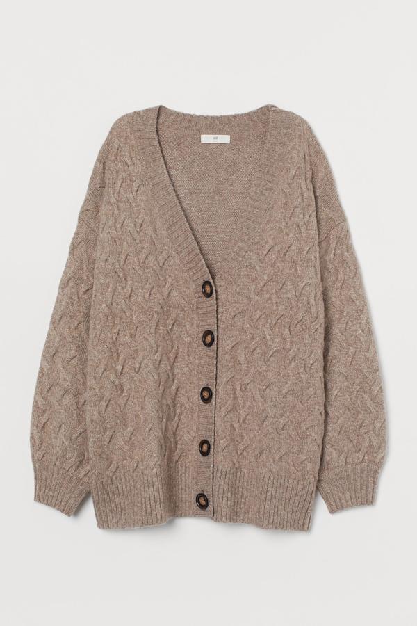 En color beige jaspeado, este cárdigan oversize de punto trenzado cuenta con mangas amplias, hombros caídos y ribete de canalé en escote, tapeta, puños y bajo. Es de H&M y tiene un precio de 39,99 euros.