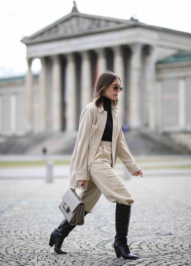 Un funcional onjunto en tonos crudos de camisa XL y pantalón por dentro de un par de botas altas de cuero negro.