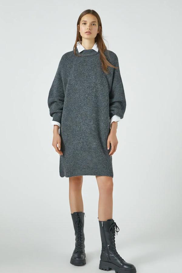 Disponible en gris, camel o crudo, este vestido de punto de manga larga con cuello perkins tiene un precio de 18,39 euros.