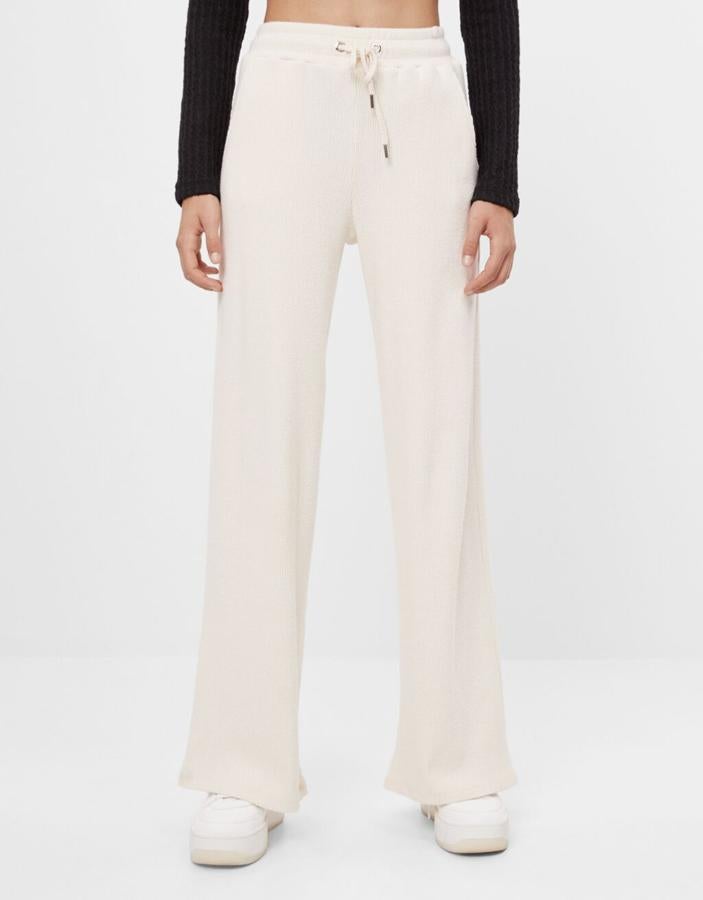 Diseño acanalado para este pantalón en color crudo de Bershka que también podemos encontrar en gris. Con cintura elástica ajustable con cordón, cuesta 19,99 euros y está disponible entre las tallas XS y XL, aunque algunas se están agotando.