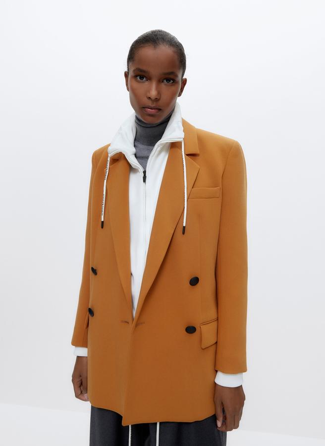 En color mostaza, esta blazer cruzada con bolsillos laterales con solapa viene con doble botonadura a contraste en negro de diseño metálico con efecto engomado, que también están presentes en los puños. De 159 euros ha pasado a costar 119,25 euros y podemos encontrarla entre las tallas XS y L.