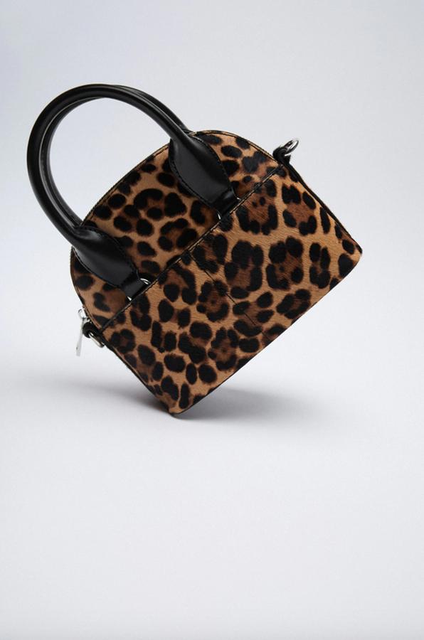 En formato mini bowling de piel con pelo corto en estampado de leopardo, este bolso de Zara viene con dos bolsillos delanteros y dos traseros, asas de mano y asa de hombro en cadena en combinación de materiales. Con cierre superior de cremallera, cuesta 29,95 euros.