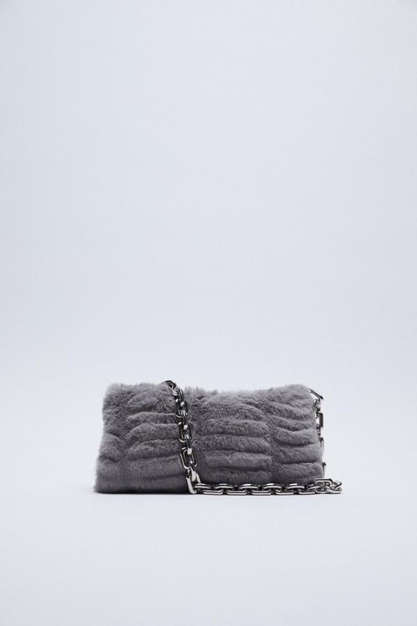 Cartera de mano con pelo y cadena de eslabones metálicos, de Zara (25,95 €).