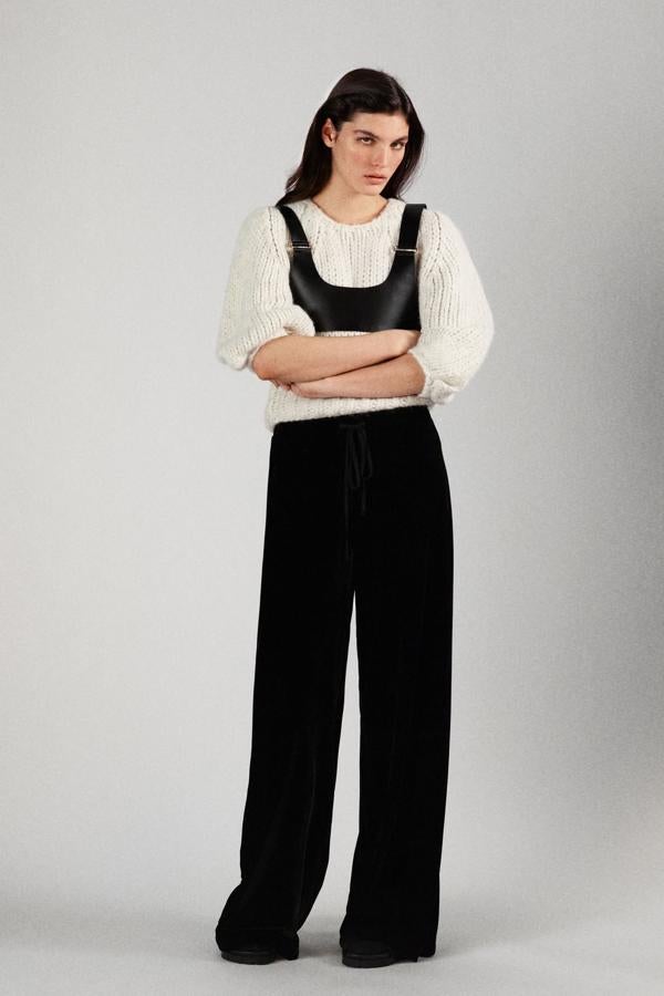 Top de cuero negro sobre jersey de punto grueso y pantalones anchos de vestir, todo de Zara.