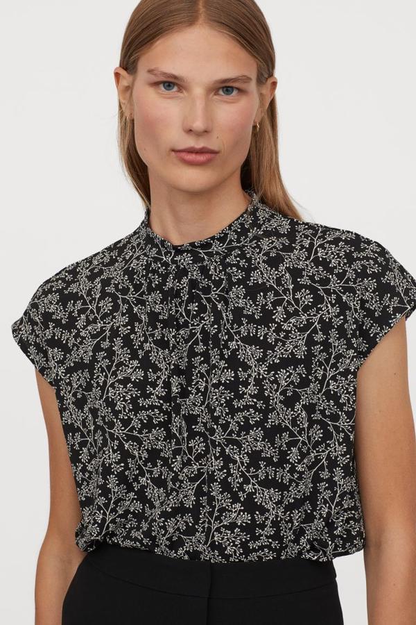 Fondo negro con estampado de flores en color blanco para este top de cuello elevado de doble capa confeccionado en punto fluido con mangas japonesas de H&M. Con fruncidos frontales en el escote, tiene un precio de 9,99 euros y está disponible entre las tallas XS y XL.