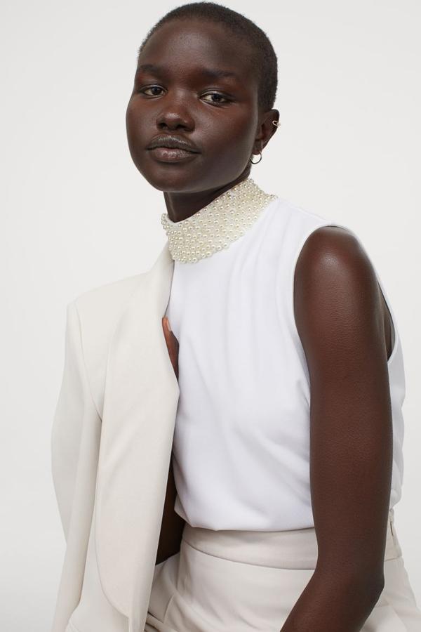 Disponible únicamente en la web de H&M, este top blanco con cuello elevado con detalle de perlas, sin mangas y con cierre de lágrima oculto en la nuca, tiene un precio de 24,99 euros y está disponible entre las tallas XS y XXL.