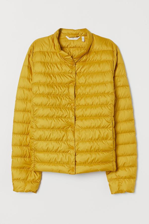 En color amarillo, esta chaqueta con relleno de plumón reciclado (70%) y plumas recicladas (30%) cuenta con diseño entallado y cuello elevado. Incluye una bolsa a juego para guardar y tiene un precio rebajado de 23,99 euros. Es de H&M.