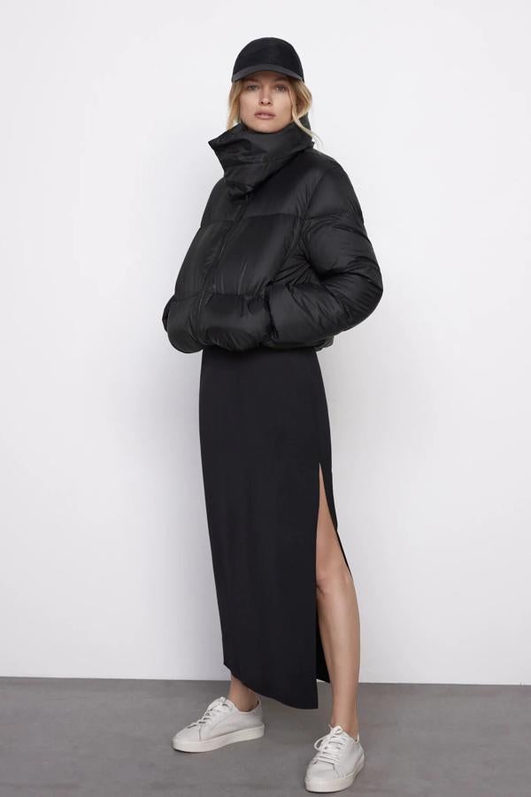 En color negro, este plumífero corto con relleno de pluma y plumón cuenta con cuello subido con capucha y bajo ajustable con cordones elásticos. Es de Zara y tiene un precio de 49,95 euros.