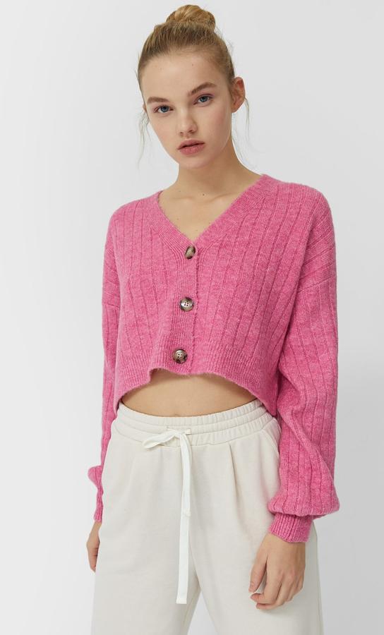 En color rosa chicle, este cárdigan cropped de punto con escote de pico y cierre con botones delanteros tiene un precio de 19,99 euros.