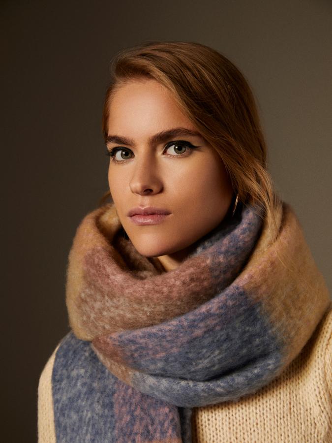 De tacto suave y acabado de flecos, esta bufanda de cuadros de Lefties en tonos beige, marrón y azul cuesta 12,99 euros.