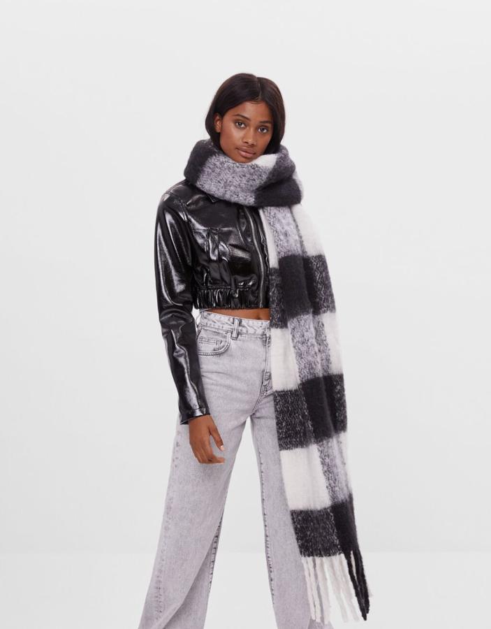 Con estampado de cuadros en blanco y negro, esta bufanda con flecos de Bershka tiene un precio de 12,99 euros.