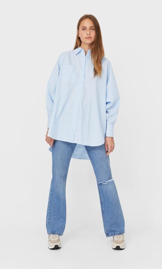 En azul celeste, con cuello de solapa, mangas largas y diseño amplio, esta camisa de popelín de Stradivarius tiene un precio de 19,99 euros y está disponible entre las tallas XS y L.