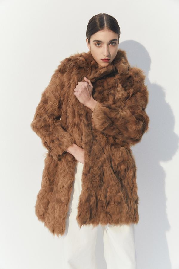 Diseño midi con cuello solapa con muescas, bolsillos frontales de ojal y pelo rizado de cordero para este abrigo en color whisky que tenía un precio de 189,99 euros y ahora podemos comprar por 132,95 euros.