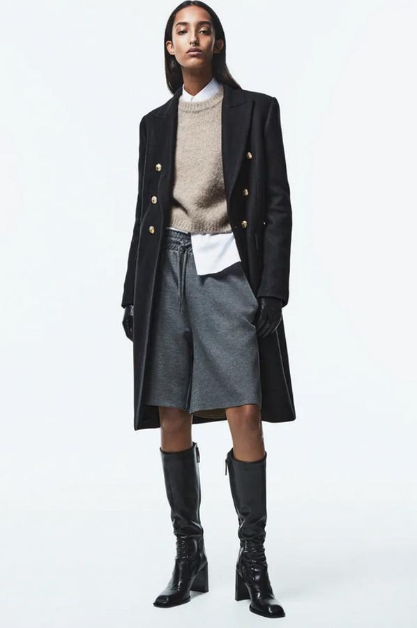 Diseño midi, cuello solapa y bolsillos delanteros con solapa para este abrigo negro con abertura en la espalda y cierre frontal con botones metálicos en dorado. De 99,95 euros ha pasado a 59,97 euros.