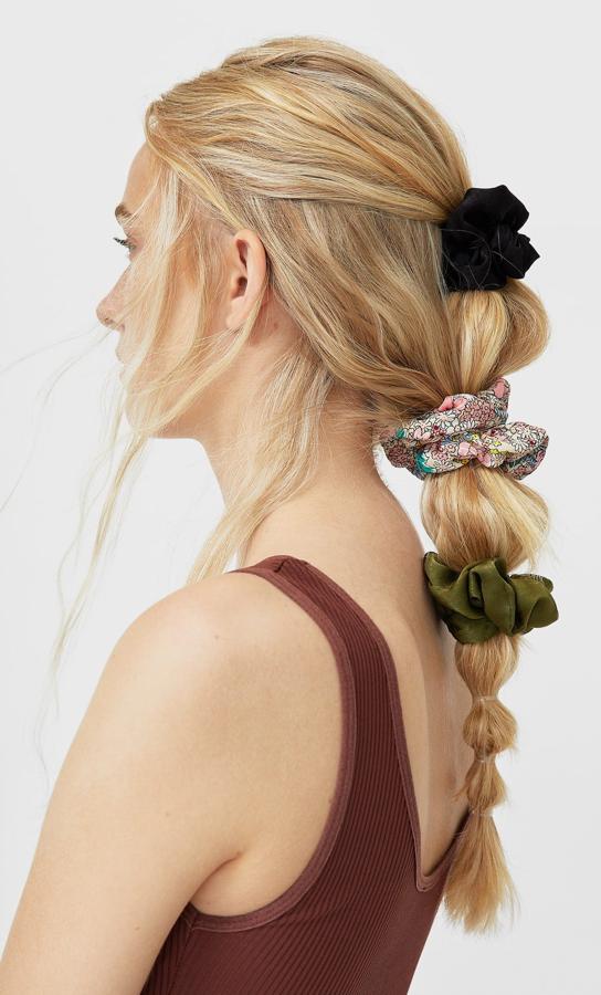 Si buscas algo más sofisticado puedes combinar dos peinados en uno y obtener este bonito resultaod. Recoge con un coletero de tela la parte superior de la cabeza y después hazte una coleta burbuja con todos mechones sobrantes. Añade un par de coleteros más y.... ¡Listo! El set de 3 cuesta 5,99 euros.