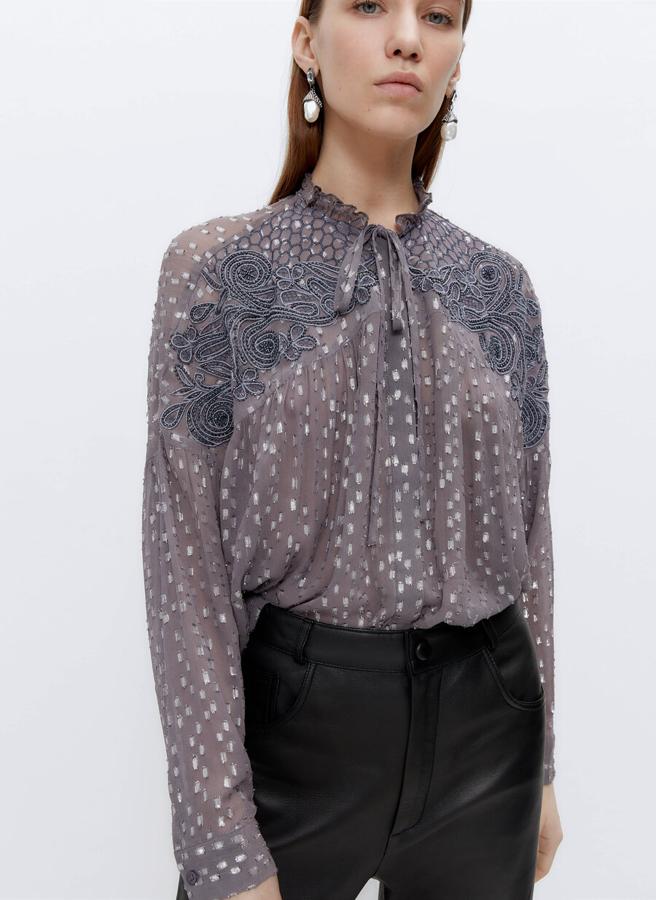 Con diseño de cuello redondo y mangas largas esta camisa en color gris con apliques en plata y bordado frontal, viene con cierre de botones frontal ocultos por tapeta. Tiene un precio de 89 euros y está disponible en las tallas S y M.