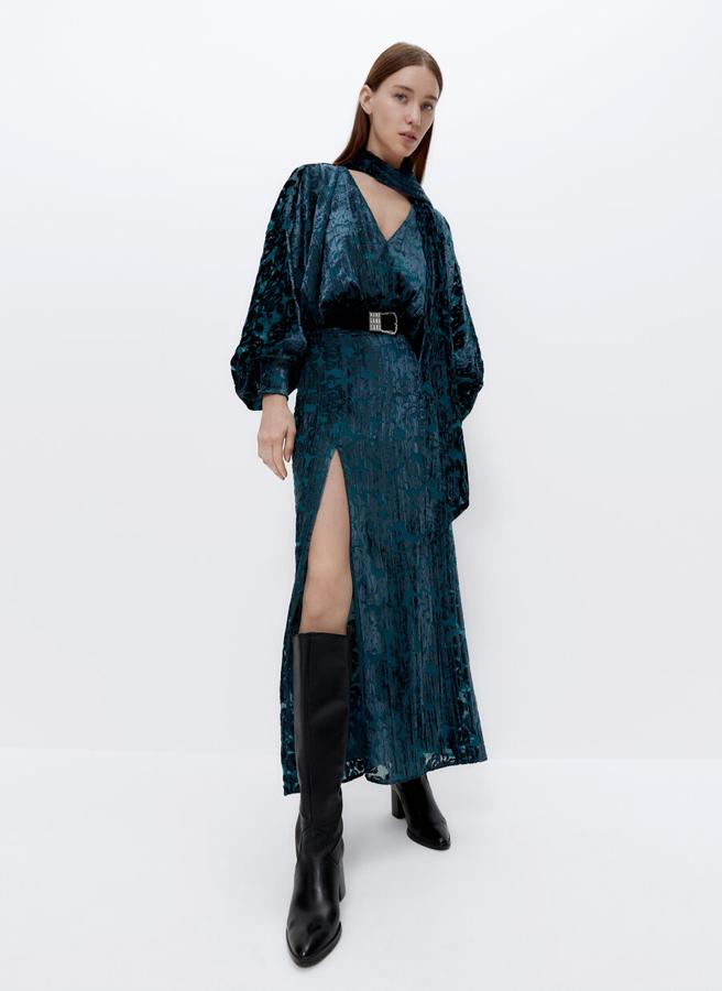 En verde azulado, confeccionado en tejido devorado de flores, escote de pico y lazada grande en el cuello, este vestido de cintura ajustada y bajo con abertura lateral en el frontal viene con la espalda con abertura central. Tiene un precio de 159 euros y está disponible entre las tallas XS y L.