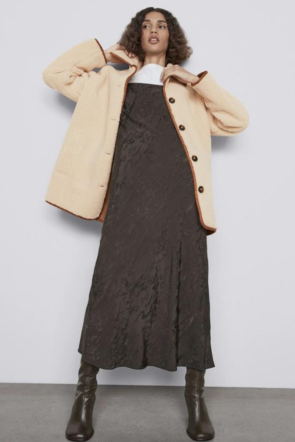 Este abrigo de borreguillo en color beige con tejido interior y vivos en contraste cuenta con bolsillos laterales y cierre frontal de botones. Es de Zara y tiene un precio de 59,95 euros.