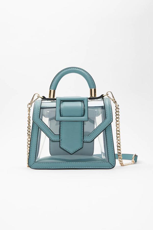 En color azul y con cuerpo de vinilo transparente, este bolso formato mini city cuenta con asa de mano tubular con detalle dorado y asa de hombro extraíble con cadena. Es de Zara y tiene un precio de 25,95 euros.