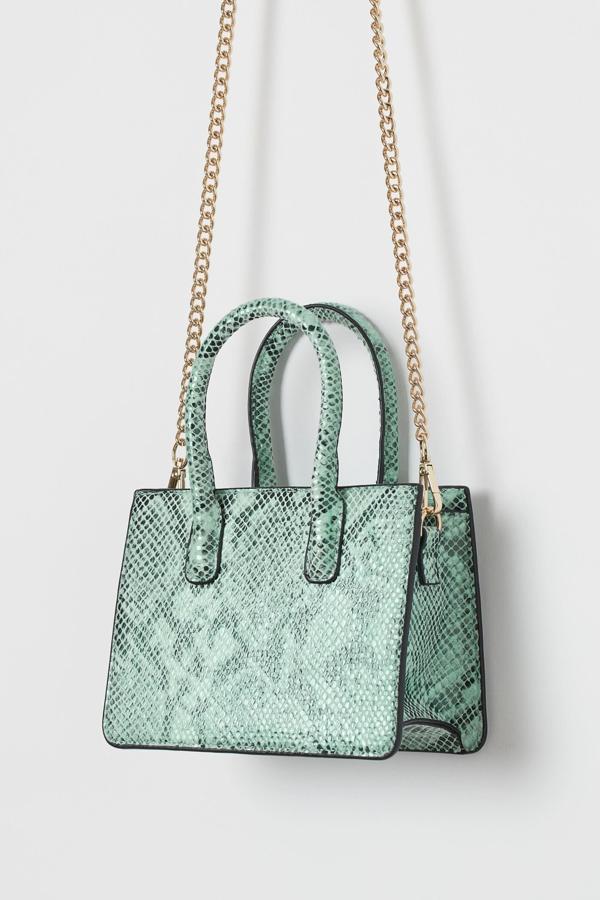 Este mini bolso rígido en piel sintética de color turquesa con efecto serpiente cuenta con dos asas cortas y una larga de cadena extraíble. Es de H&M y tiene un precio de 24,99 euros.