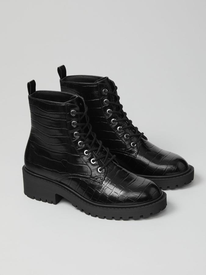 Con textura de coco en el corte y suela track, este botín de color negro con pasadores metálicos y cierre mediante cordones y cremallera lateral tiene un precio de 29,99 euros.