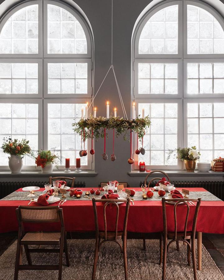 La madera, combinada con los elementos verdes de las plantas y la decoración en rojo hacen de esta propuesta de H&M Home la mesa navideña perfecta. Las sillas cuestan 99.99 euros; la alfombra de yute, 129 euros, los jarrones 27.99 euros y el mantel de lino rojo, 39.99 euros.