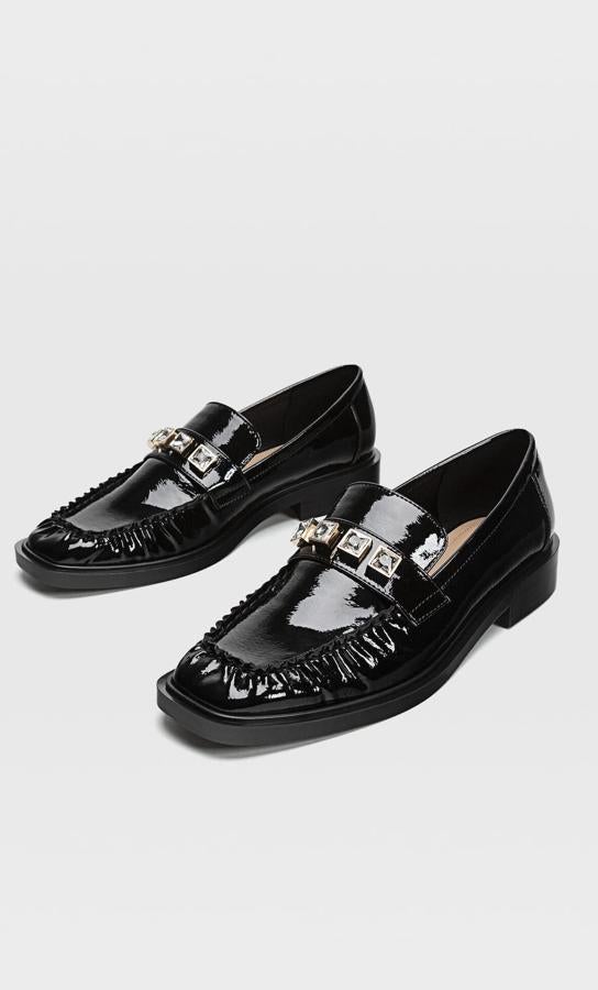 En charol y con detalles de pliegues, estos mocasines de Stradivarius nos han enamorado por sus detalles joya y son la opción perfecta para un look de noche cómodo (29,99 euros).