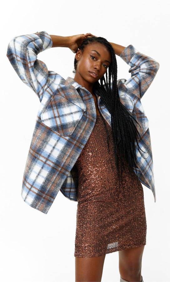 Confeccionada en punto, con bolsillos de tapeta en el pecho, cuello solapa y cierre frontal de botones a tono para esta sobrecamisa en tonos marrones y azules con bolsillos laterales ocultos en costura. Es de Stradivarius, cuesta 35,99 euros y está disponible en las tallas XS, S y M.