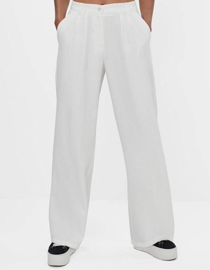 En color blanco, estos pantalones wide leg con pinzas delanteras cuentan con trabillas en la cintura y cierre mediante botón y cremallera. Son de Bershka y tienen un precio de 22,99 euros.