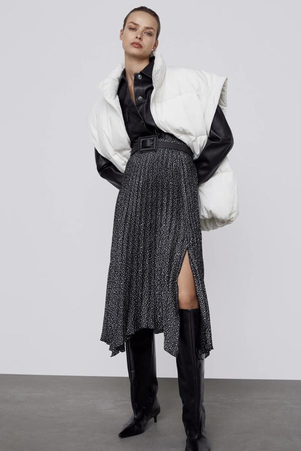 Con bajo asimétrico y detalle de cinturón con hebilla cuadrada, esta falda plisada en negro y crudo cuenta con abertura en la parte delantera y cierre con cremallera en la espalda. Es de Zara y tiene un precio de 29,95 euros.