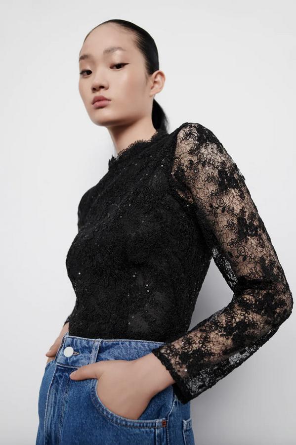 Esta blusa de cuello subido y manga larga confeccionada en diseño de encaje viene con aplicación de lentejuelas y cuerpo interior a tono en color negro. Con cierre en la espalda, cuesta 29,95 euros y está disponible en las tallas S, M y L.