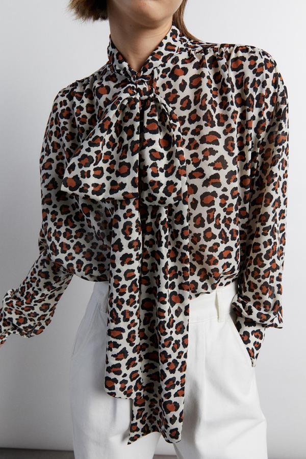 Manga larga y lazada en cuello para esta camisa de Sfera con fondo en color piedra y estampado de leopardo en marrón y negro. Tiene un precio de 25,99 euros y podemos encontrarla en las tallas M y L.