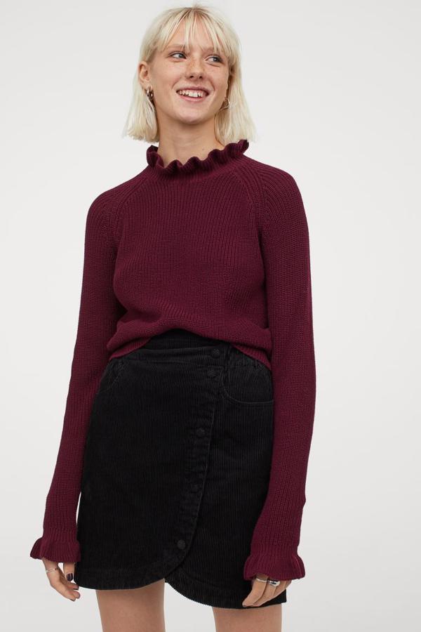 En punto de canalé suave de mezcla de algodón, este jersey en color vino de H&M que también podemos encontrar en negro viene con cuello elevado de volante y mangas raglán con volante en los puños. Cuesta 19,99 euros y podemos encontrarlo únicamente en las tallas XS y S.