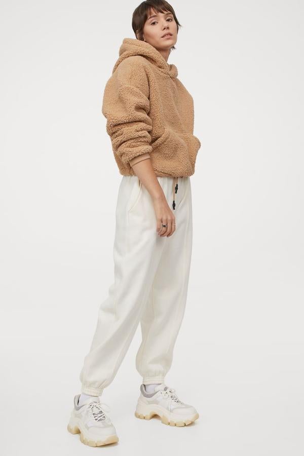 Diseño boxy en borreguito para esta sudadera beige de H&M con cordón de ajuste en el bajo, capucha forrada en punto, hombros marcadamente caídos y bolsillo de canguro en el frontal. Tiene un precio de 24,99 euros y está disponible únicamente en las tallas XS y S.