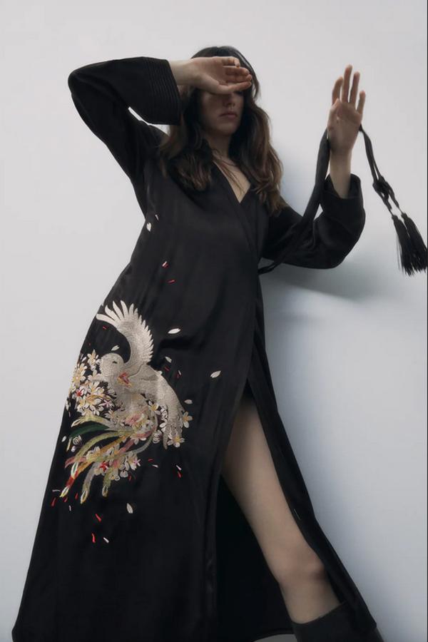 Con escote de pico y manga larga, este kimono negro de Zara con cierre frontal cruzado con botón interior y lazada acabada en borlas combinada a tono, viene con un precioso bordado en un lateral en tonos grises y verdes. Cuesta 69,95 euros y está disponible entre las tallas XS y L.