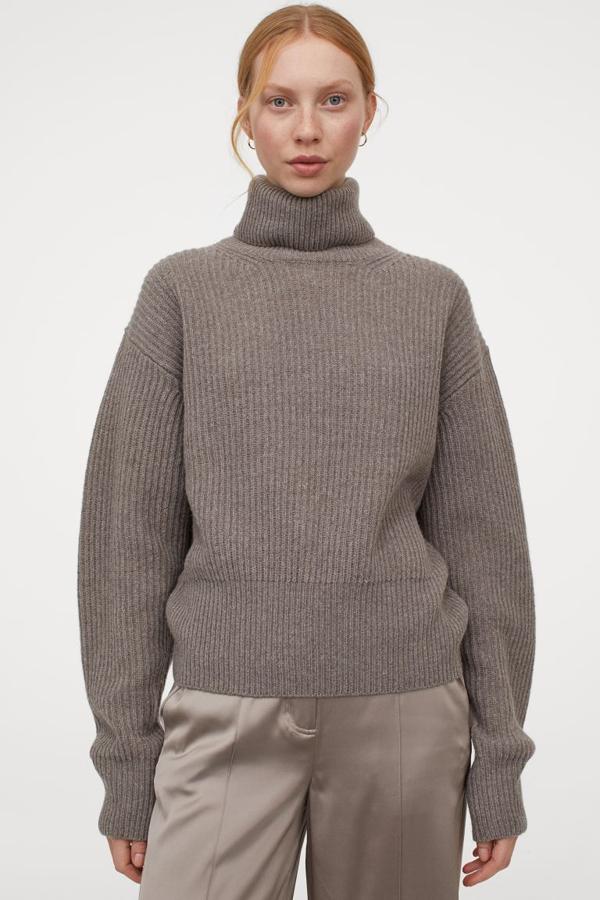 De cuello alto, en punto de canalé de lana suave con cachemira reciclada en la trama este jersey en beige grisáceo está diseñado con hombros caídos y remate de canalé en puños y bajo. Cuesta 79,99 euros y solo queda en la talla S.