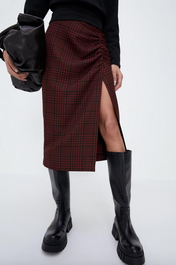 Con estampado de cuadros en negro y rojo, esta falda midi de tiro alto drapeada en delantero con detalle de abertura lateral es de Zara y tiene un precio de 25,95 euros. Está disponible entre las tallas XS y XL.