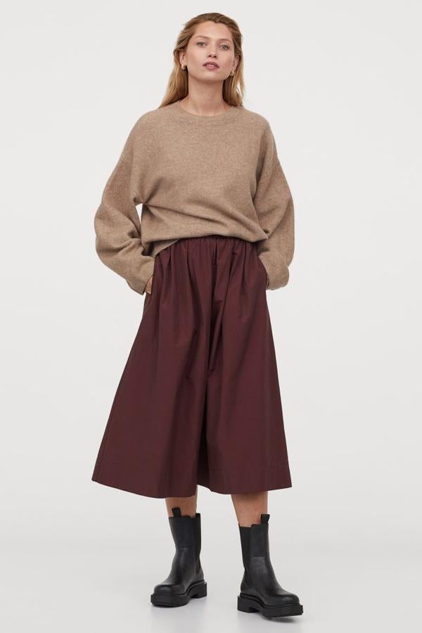 En mezcla de algodón con ligero brillo, esta falda midi de H&M en burdeos con cintura paper bag alta en elástico revestido viene con ribete de volantes y pliegues para dar volumen. Tiene bolsillos al bies discretos, cuesta 29,99 euros y está disponible entre las tallas XS y XXL.