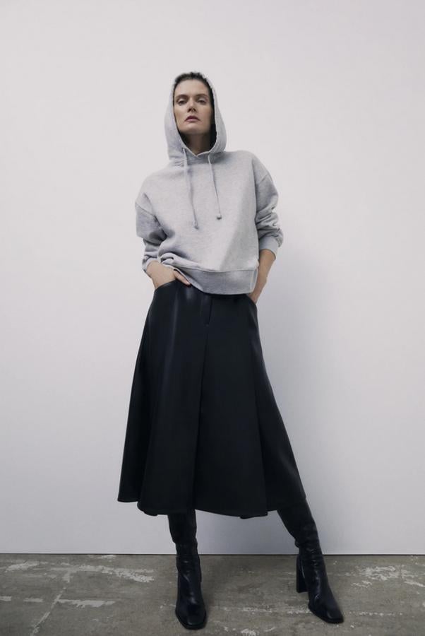 Esta falda negra de Zara en efecto piel viene con bajo acabado en evasé para dar volumen a la prenda y tiene bolsillos laterales al bies. Con cierre frontal de botón, cremallera y gancho metálico, cuesta 25,95 euros y está disponible entre las tallas XS y XL.